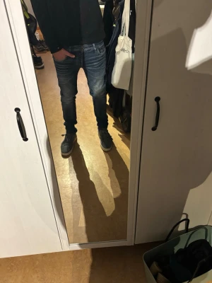 Blå slim fit jeans med slitningar - Säljer ett par blå slim fit jeans med snygga slitningar och tvättade detaljer på låren och knäna. Jeansen har klassisk femficksdesign och normal midja. Perfekta för en avslappnad och trendig look. 28x32 i storlek 