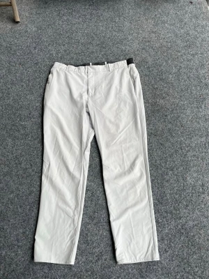 Ljusgrå chinos med normal passform - Snygga ljusgrå chinos med rak och normal passform. Byxorna har enkel design utan synliga detaljer och är tillverkade i ett mjukt bomullsmaterial. Perfekta för dig som vill ha en clean och stilren look.