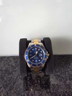 Till ditt pris😉 - Stilren herrklocka med blå urtavla, gulddetaljer och silverfärgad länk. Klockan har datumvisning och vridbar ring i blått och guld. Armbandet är i metall med både guld- och silverfärgade länkar. Perfekt accessoar för dig som vill sticka ut. Länkar sickas med.