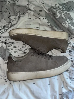 Gråa sneakers i mocka - Säljer ett par gråa mocka skor från Jack & Jones! De är använda ett tag och är lite smutsiga men kan tvätta dem om det behövs, samt lite slitna men ej något hål! Köpta för 999!