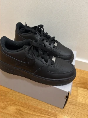 Helvita svarta sneakers i läder - Snygga helsvarta sneakers i läder med klassisk siluett och perforerad tåbox. Skorna har svarta skosnören, diskret logga på sidan och metall-detalj vid snörningen. Passar perfekt till streetwear och har en chunky sula för extra attityd. Oanvända skor 