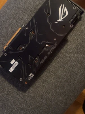 ASUS ROG Strix grafikkort - Säljer ett ASUS ROG Strix grafikkort med svart design och tre stora kylfläktar. Kortet har snygga detaljer och robust byggkvalitet, perfekt för gaming och tunga datoruppgifter. Passar i de flesta stationära datorer med PCIe-anslutning.