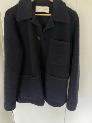 Svart overshirt från A Day's March - Aldrig använd!!!!Stilren svart overshirt från A Day's March med klassisk krage, tre stora utanpåfickor och knäppning framtill. Tillverkad i ett tjockare ullmaterial som ger en snygg och avslappnad look. Perfekt lager-på-lager-plagg för kyligare dagar.