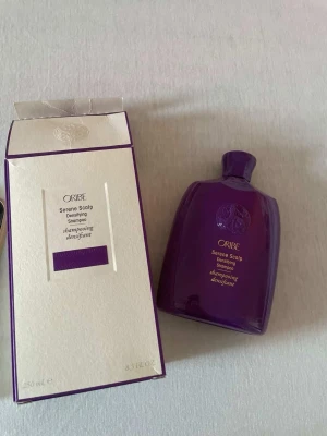 Oribe Serene Scalp Densifying Shampoo - Oribe Serene Scalp Densifying Shampoo i en lyxig lila plastflaska, 250 ml. Kommer med matchande vit och lila kartong. Schampot är speciellt framtaget för att stärka och ge volym till håret samt vårda hårbotten. Perfekt för dig som vill boosta hårets fyllighet.