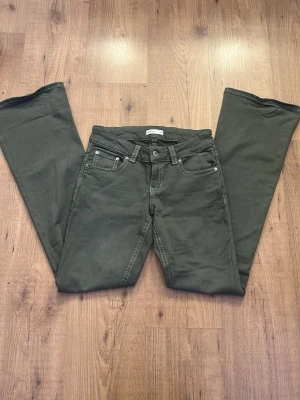 Mörkgröna bootcut jeans Perfect Jeans - Snygga mörkgröna bootcut jeans från Perfect Jeans med kontrastsömmar och klassisk femficksmodell. Jeansen har normal midja och är tillverkade i ett mjukt bomullsmaterial med lite stretch för extra komfort. De är aldrig använda.