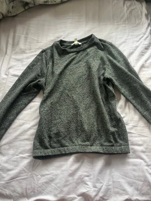 Grå stickad tröja med rund hals - Mysig grå stickad tröja med rund hals och långa ärmar. Tröjan har en enkel och stilren design, perfekt för lager på lager och passar till det mesta. Materialet ser ut att vara mjukt och bekvämt, vilket gör den skön att bära under kyligare dagar.