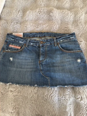 Blå jeanskjol från Superdry - Säljer en blå jeanskjol från Superdry. Kjolen säljs pågrund av att storleken var för stor för mig💕 midjemått:42,längd:27. jättefin 2000s stil kjol perfekt för sommaren. Inga hål , jättefint skick💝💐