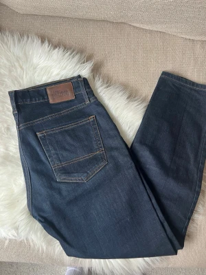 Tommy Hilfiger Jeans - Ett par Mörkblå Tommy Hilfiger jeans i storlek 33/30, jag är 177cm och längden passar mig bra. De är i mycket fint skick och har en smalare passform.