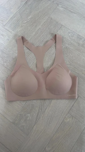 Calvin Klein bra - Selling a beautiful Calvin Klein sports bra in a soft dusty pink/nude colour.  ✨ Never worn ✨ Size XS ✨ Lightly padded cups ✨ Seamless, smooth design for maximum comfort ✨ Racerback style for support and freedom of movement ✨ Calvin Klein logo details front and back ✨ Perfect for gym, yoga, pilates, walking or everyday wear  Condition: New condition, never worn.  Smoke-free and pet-free home.