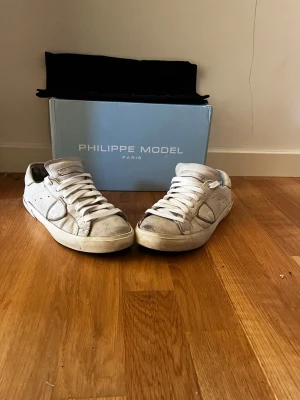 Philippe Model vita sneakers i skinn - Snygga vita sneakers från Philippe Model i äkta skinn med klassisk låg siluett. Skorna har vita snören, diskret logga på plösen och en robust gummisula. Perfekta för dig som gillar stilrena och exklusiva sneakers med en urban vibe. vid frågor eller funderingar skicka ett dm pris kan diskuteras. 