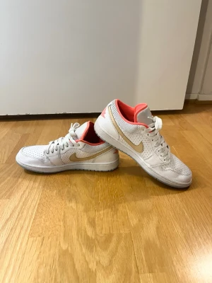 Nike Air Jordan 1 Low - Storlek 41 - Säljer ett par stilrena Jordan 1 Low i den populära färgkombinationen White/Sesame med snygga korallfärgade detaljer. En tidlös sneaker som är lätt att matcha och passar lika bra till vardags som till en mer uppklädd outfit. Skorna är i bra skick med normalt slitage från användning. Lite uppslitet på tygget vid den övre delen av den ena skon som ni ser på bilderna.
