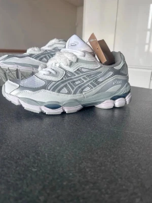 Vita Asics sneakers med mesh och skinn - Snygga vita Asics sneakers med detaljer i silver och grått. Ovandelen är i mesh och skinn för en sportig vibe och sulan är chunky med coola former. Klassisk Asics-logga på sidan och tungan. Perfekta för dig som gillar streetwear och bekväma skor. (HELT NYA) (har ej box) (A Klass Imitation)
