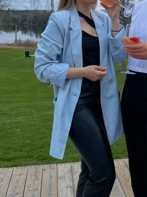 Ljusblå oversized kavaj - Trendig ljusblå oversized kavaj med två knappar framtill och klassisk krage. Kavajen har raka axlar och långa ärmar, perfekt för en stilren look. Passar snyggt till både byxor och kjol.