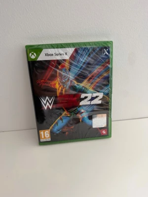 WWE 2K22 Xbox Series X spel - WWE 2K22 till Xbox Series X med grön plastbox och färgstark omslagsbild på en brottare i mask. Spelet har PEGI 16-märkning och är utvecklat av 2K. Perfekt för dig som gillar wrestling och actionfyllda matcher. Helt ny