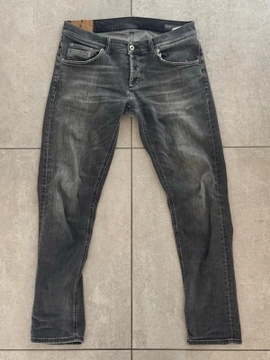 Grå slim fit jeans från Dondup - Snygga grå slim fit jeans från Dondup med slitna detaljer och klassisk femficksmodell. Jeansen har en något tvättad look och raka ben. Perfekta för en avslappnad och trendig stil. Jeansen är i strl 34 men passar ungefär 32/32. Har lagats i skrevet en gång pga spricka men är knappt så att det syns. Litet hål nere på byxbenet efter användning men inget man märker heller 