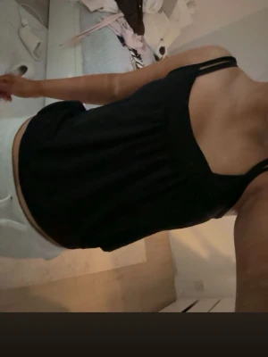 Svart linnetopp  - Säljer en svart linnetopp med breda axelband och lös passform. Toppen har en enkel design utan mönster och är perfekt för varma dagar. Materialet känns mjukt och bekvämt mot huden.