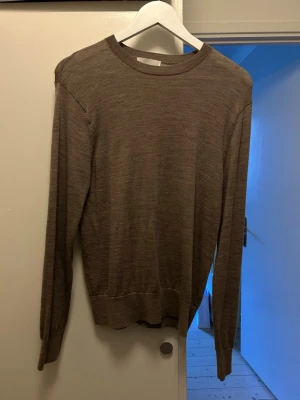 Brun tunn stickad tröja Sandö - Säljer en tunn, brun stickad tröja från Sandö i storlek S. Tröjan har rund halsringning, långa ärmar och ribbade muddar vid ärmslut och nederkant. Perfekt för lager på lager och enkel att matcha med olika outfits.