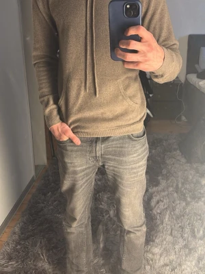 Kashmir hoodie från john henric - Säljer en stilren beige kashmir hoodie från john henric med huva och dragsnören. Hoodien har en klassisk känguruficka framtill och ribbade muddar vid ärmslut och nederkant. Perfekt för en avslappnad och trendig look.