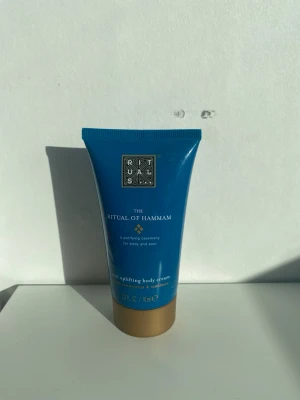 Rituals The Ritual of Hammam body cream - En blå tub med The Ritual of Hammam body cream från Rituals. Innehåller 70 ml och har en guldig kork. Krämen är berikad med eukalyptus och rosmarin för en fräsch och upplyftande känsla. Perfekt för dig som vill ha en lyxig kroppskräm utan parabener eller mineralolja. Endast testad.