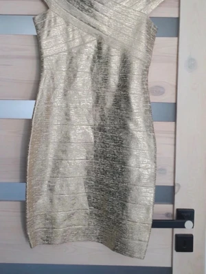 Guldig omlottklänning i metallic - Säljer en kort, vintage guldig bandage klänning. Köpt secondhand. Storleken är xs men passar s också skulle jag säga. 