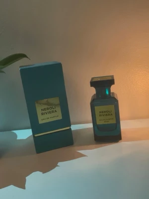 Neroli Riviera Eau de Parfum 80ml - Snygg parfymflaska i mörkblått glas med matchande förpackning. Neroli Riviera Eau de Parfum har en elegant, fyrkantig design och guldiga etiketter på både flaska och ask. Innehåller 80 ml doft som ger en lyxig känsla. Pris kan diskuteras ungefär 68 ml kvar