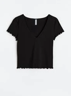 Svart croppad topp med v-ringning - Snygg svart croppad topp med v-ringning och korta ärmar. Toppen har ribbad struktur och vågiga kanter vid ärmslut och nederkant.