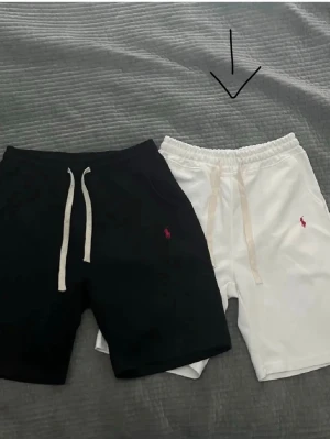 Vita shorts från Polo Ralph Lauren - Vita shorts från Polo Ralph Lauren med klassisk broderad logga i rosa på benet. Shortsen har resårmidja med snörning och är tillverkade i mjuk bomull, perfekta för sommardagar. Enkel och stilren design som passar till det mesta.