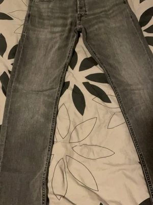 Gråa slim fit jeans Jack & Jones - Snygga gråa slim fit jeans från Jack & Jones, modell Glenn. Jeansen har klassisk femficksdesign, dragkedjegylf och svarta sömmar. Perfekta för dig som gillar en modern och stilren look.