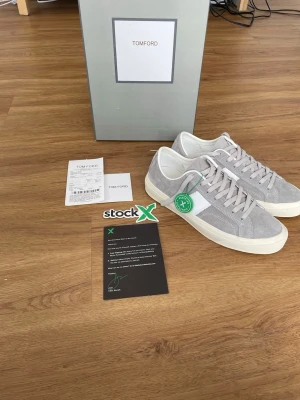 Tom Ford Cambridge  - Snygga sneakers från Tom Ford i grå mocka med vita detaljer och vit sula. Klassisk låg modell med vita skosnören och diskret branding på sidan. Perfekta för dig som gillar stilrena och exklusiva sneakers. Obs de e f@k3!!