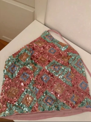 Paljettprydd rosa och blå halterneck topp - Säljer en färgglad halterneck topp täckt av paljetter i rosa, blått och guld. Toppen har ett geometriskt mönster och knyts i nacken. Perfekt för dig som vill sticka ut och älskar glitter och färg.