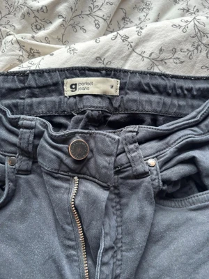 Svarta bootcut jeans från Gina  - Säljer ett par svarta bootcut jeans med hög midja från Gina tricot. Jeansen har utsvängda ben och bälteshällor. Jeansen har varit använda som ni ser på bilderna så har de ”töjts ut” längst ner på benen som nu ser på ena bilden har de blivit slitet. 