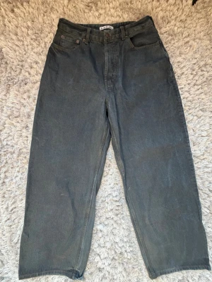 Mörk blå Baggy Waxed jeans från Acne Studios - Säljer ett par svarta mörkblå vaxade jeans från Acne Studios. Jeansen har klassisk femficksmodell, hög midja och raka ben. Tillverkade i kraftig denim med bälteshällor och knappgylf. Perfekta för en clean och stilren look. Aldrig använda, toppskick. Storlek L