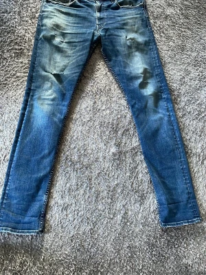 Blå slitna jeans från Ralph lauren - Säljer ett par blå jeans från Ralph lauren med snygga slitningar och tvättade detaljer framtill. Jeansen har fem fickor, normal midja och smal passform. Perfekta för en avslappnad och trendig look. Materialet är klassisk denim i bomull.