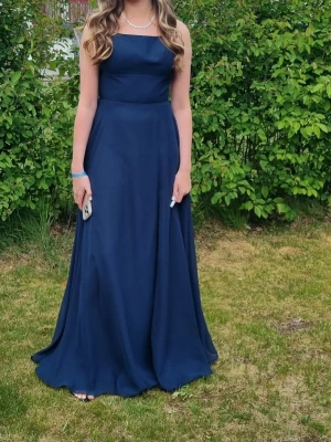 Balklänning från JJ House - Marinblå balklänning, halterneck, öppen rygg med snörning.