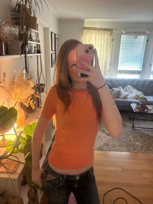 Orange tight kortärmad topp - Snygg orange topp med tight passform och korta ärmar. Enkel och stilren design utan mönster eller detaljer, perfekt att matcha med jeans eller kjol. Materialet känns mjukt och stretchigt, vilket gör den bekväm att bära hela dagen.