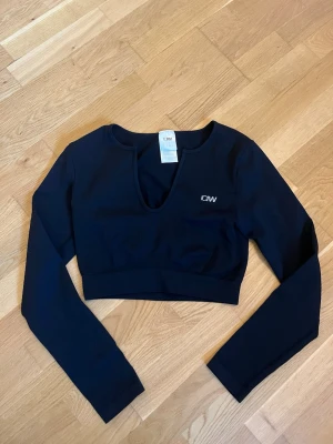 Svart croppad träningstopp ICANIWILL - Svart croppad träningstopp från ICANIWILL med lång ärm och ribbad struktur. Perfekt för gymmet eller annan träning, tillverkad i stretchigt syntetmaterial för bästa komfort. Säljer pga rensning och har används en gång.