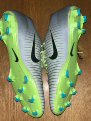 Nike Mercurial fotbollsskor grå/neon - Säljer ett par Nike Mercurial fotbollsskor i grått med neon- och turkosa detaljer. Änvända ett få tal gånger. Nästan helt nya. Perfekta för dig som vill sticka ut på matchen!