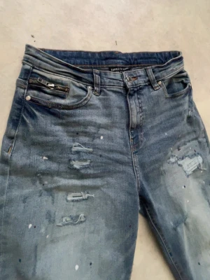 Blå slitna jeans från Supply & Demand - Säljer ett par blå jeans från Supply & Demand helt nya de passar 13-15 åringar