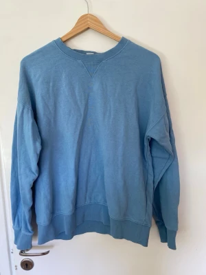 Blå sweatshirt från Lindex - En enkel och snygg blå sweatshirt från Lindex i storlek 158/164. Tröjan har rund halsringning med ribbade muddar vid hals, ärmslut och nederkant. Perfekt för en avslappnad och stilren look. I storlek 16t o h i myck ett bra skick