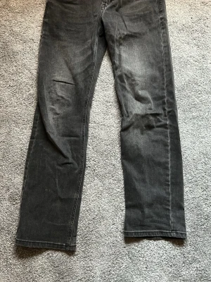 Svarta raka jeans - Säljer ett par svarta jeans med rak passform och klassisk femficksdesign. Jeansen har en lätt tvättad look och är tillverkade i denim. Perfekta för dig som gillar en enkel och stilren stil.