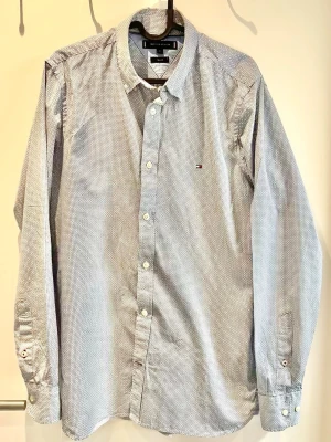 Slim fit skjorta från Tommy Hilfiger - Snygg ljusblå skjorta från Tommy Hilfiger i slim fit The skjortan har diskret mönster, klassisk krage, knappar framtill och liten logga på bröstet. Perfekt till jeans eller chinos för en clean look.