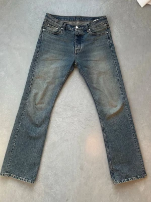 HOPE Rush raka jeans blåa  - Klassiska blå jeans från HOPE med rak passform.  Jeansen har en lätt tvättad look och normal midja. Tillverkade i denim med subtila slitningar för en avslappnad stil. Perfekta för dig som gillar en enkel och tidlös look. W 29 L 32. Modellen heter rush