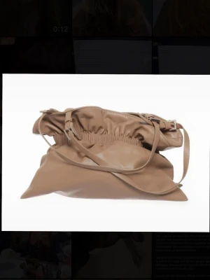 Beige axelväska från Zara - Säljer en beige axelväska i mjukt skinn med justerbar axelrem och snygg rynkad öppning. Väskan har en minimalistisk design och passar perfekt för dig som gillar stilrena accessoarer. Enkel att matcha med olika outfits.