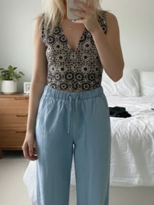Svartvit mönstrad linnetopp Gina Tricot - Säljer en snygg linnetopp från Gina Tricot i storlek S. Toppen är svartvit med ett unikt geometriskt mönster och har v-ringning. Den är ärmlös och har en figurnära passform, perfekt att styla med jeans eller kjol.