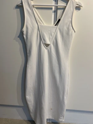 Vit ärmlös långklänning - Stilren vit långklänning med djup v-ringning både fram och bak. Klänningen är ärmlös och har en kroppsnära passform som framhäver siluetten. Så snygg och skönt klänning, endast använd 1 gång! Två fläckar men som sjävklart tas bort innan jag skickar den!!