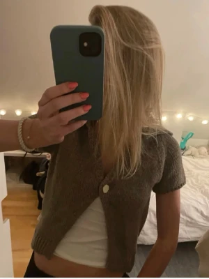 Kort brun stickad kofta - Säljer en kort, stickad brun kofta med en gullig knapp framtill. Koftan har korta ärmar. Inte mina bilder❤️ skriv gärna om ni vill ha mer bilder eller har frågor❤️❤️