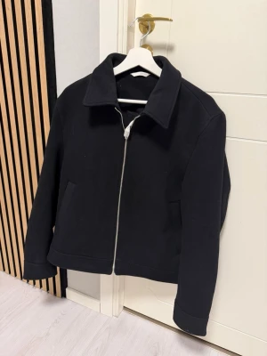 Vårjacka Zara helt ny - Stilren svart jacka med rak passform och klassisk krage. Jackan har en tydlig dragkedja framtill och två sidofickor. Perfekt för dig som gillar enkel och clean stil.