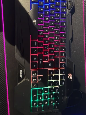 RGB-tangentbord från Havit - Snyggt svart gamingtangentbord från Havit med RGB-belysning i flera färger. Tangentbordet har en modern design med tydliga knappar och bakgrundsbelysning i blått, rött, grönt och gult. Perfekt för gaming eller datoranvändning där stil och funktion är viktigt.