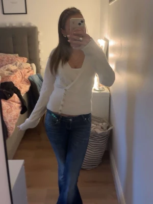 Vit omlottkofta med knappar - Säljer en vit omlottkofta med djup v-ringning och dekorativa knappar framtill. Använd fåtal gånger, inga defekter. Storlek M men funkar som xs/S