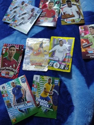 Samling fotbollskort och Pokémonkort - Säljer en blandad samling med fotbollskort från Topps och ett Pokémonkort med Flareon EX. Fotbollskorten har färgglada motiv och visar olika spelare från internationella lag. Pokémonkortet har metallic-effekt och motiv av Flareon och Jolteon.